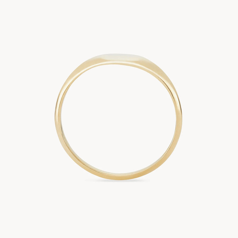 A close-up of the bluboho Loyalty signet ring - 10k yellow gold, standing upright on a plain, light-colored background. The ring features a clean, minimalist design with a flat top and smooth, polished surface, and is engravable.