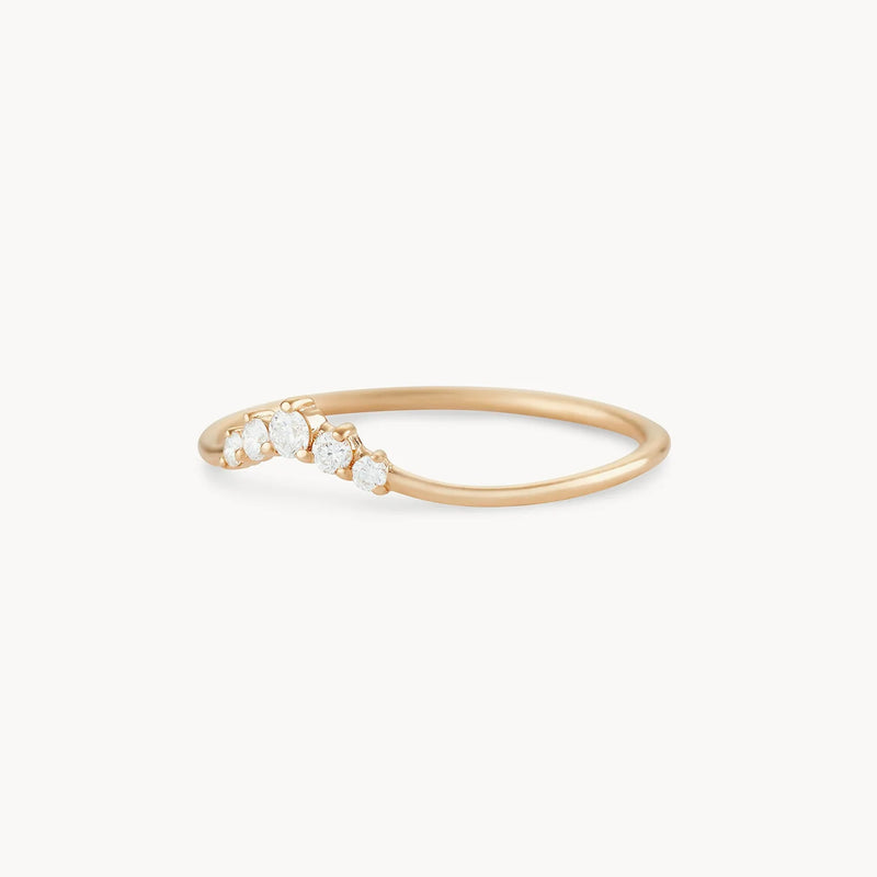 Introducing the Kismet Serendipity Ring by bluboho: This elegant 14k yellow gold ring features a slightly curved band adorned with five small, round white diamonds arranged in a graduated pattern. With its minimalistic and sophisticated design, this piece offers a subtle touch of sparkle against a plain white background.