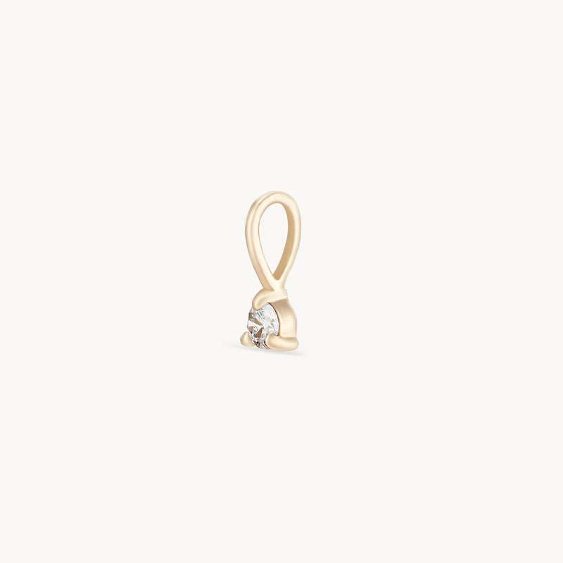 The Serendipity April Birthstone Charm by bluboho is a small, elegant 10k yellow gold charm featuring a simple loop design at the top and holding a single, sparkling round diamond securely in its setting. The charm is displayed against a plain white background.