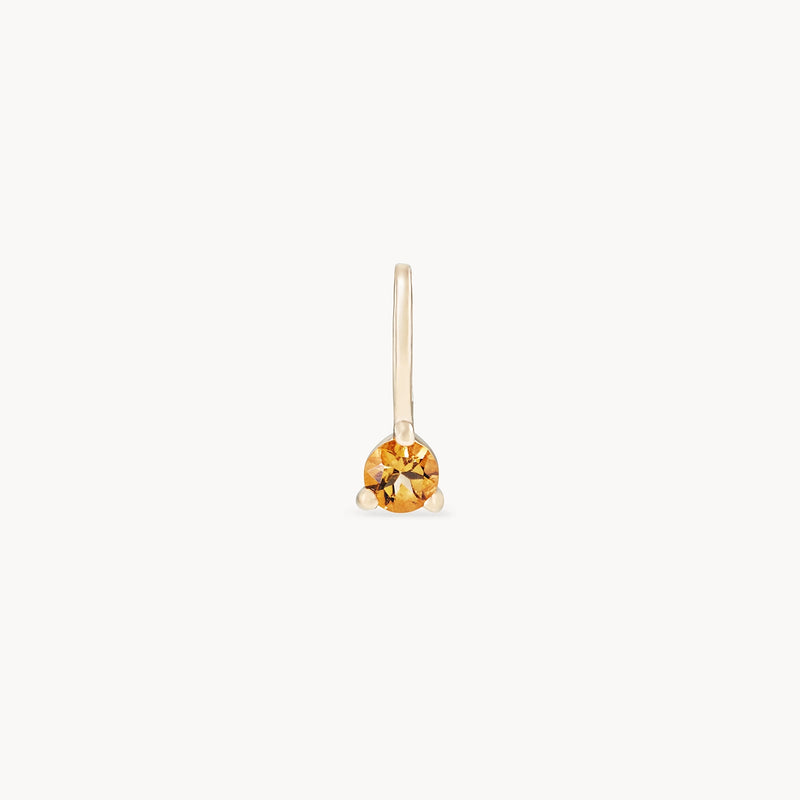 A single earring from bluboho, featuring the Serendipity November Birthstone Charm with a round citrine gemstone set in 10k yellow gold. The minimalist design includes a thin gold hook and is displayed against a plain white background.