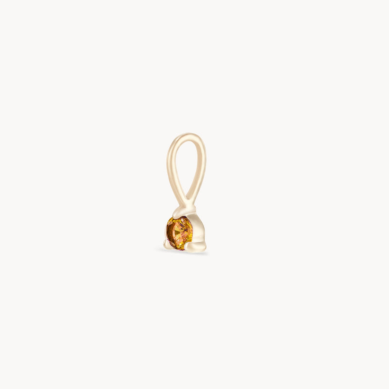 The Serendipity November Birthstone Charm by Bluboho is a small, elegant gold pendant featuring a single round citrine gemstone. Crafted in 10k yellow gold, the pendant boasts a smooth, looped bail for effortless attachment to your chain or bracelet. The plain white background accentuates the charm's simple yet sophisticated design.