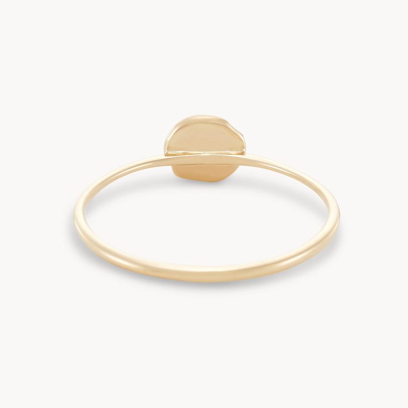 The tiny tree of life ring by bluboho is crafted from 14k yellow gold and features a small, round, slightly irregularly-shaped charm at its top center. This charm adds a subtle, polished accent to the minimalist design of the ring. Set against a plain white background, the simplicity and elegance of the ring are beautifully emphasized.