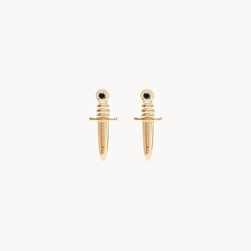 A pair of **bluboho Dagger earrings - 14k yellow gold, black diamond**, shaped like miniature daggers with tiny black gemstones at the top. The earrings are displayed against a plain white background.