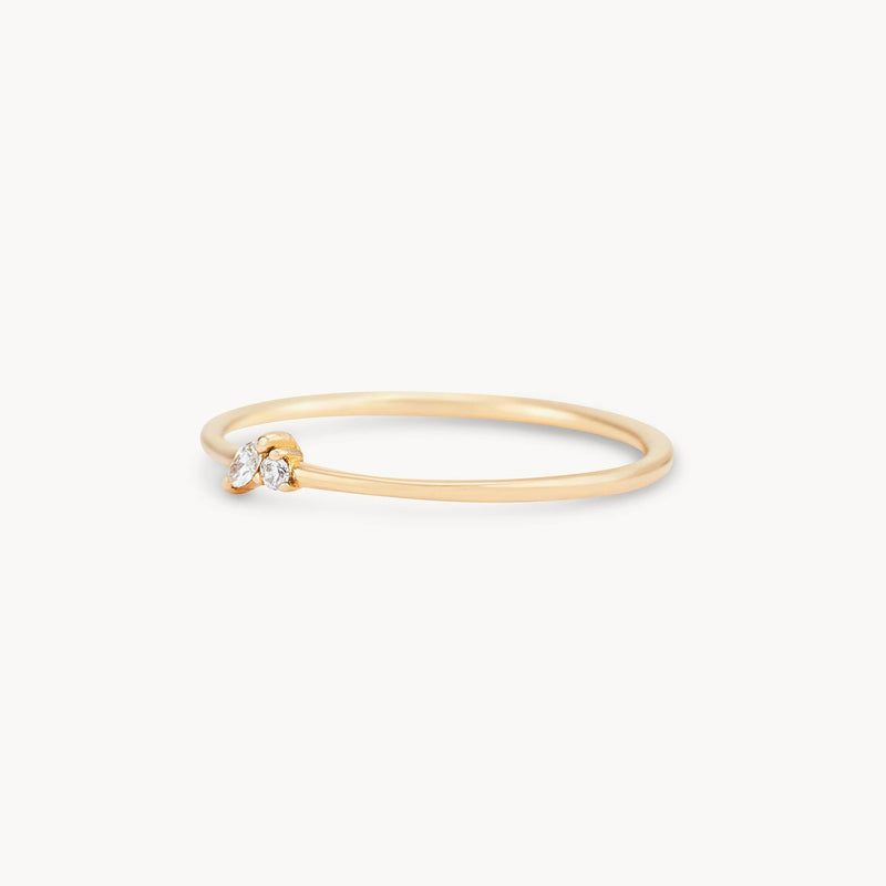 A delicate Lean on me ring - 14k yellow gold, white diamond by bluboho with a thin band featuring two small, round, white gemstones set at the top. The minimalist design accentuates the sparkle of the stones, presenting a sleek and elegant appearance against a plain white background.