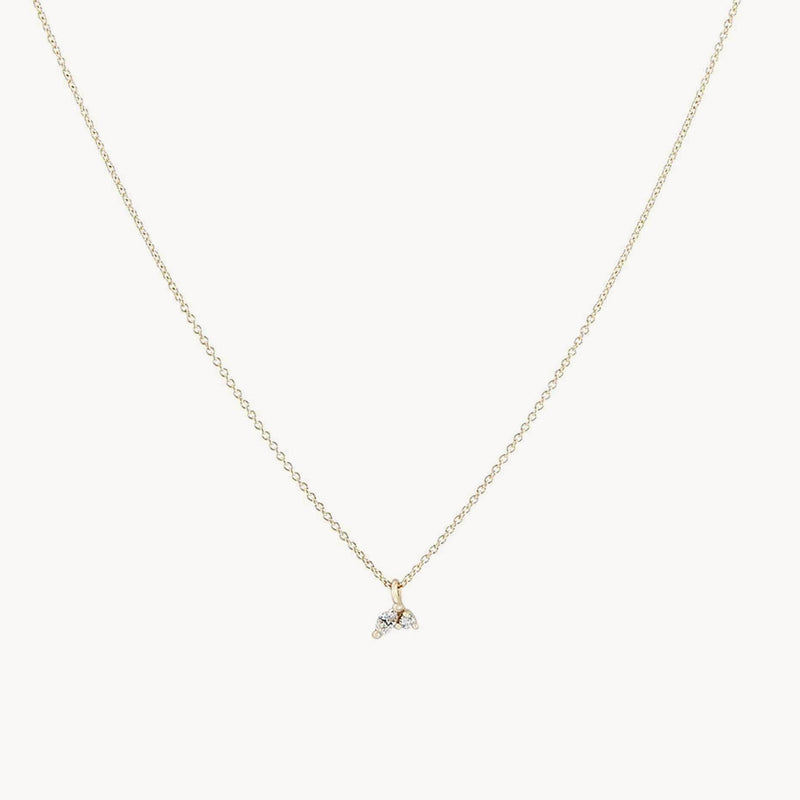 The "Lean on me diamond necklace" by bluboho features a delicate 14k yellow gold chain adorned with a small pendant showcasing three adjoining colorless diamonds in a cluster arrangement. This minimalist design exudes an elegant and subtle charm, making it perfect for both everyday wear and special occasions.