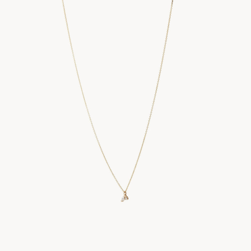 The Lean on me diamond necklace by bluboho, crafted in 14k yellow gold, hangs gracefully against a white background. This minimalist piece features a thin gold chain with a small, elegant pendant at its center, highlighting its sophisticated and understated design.