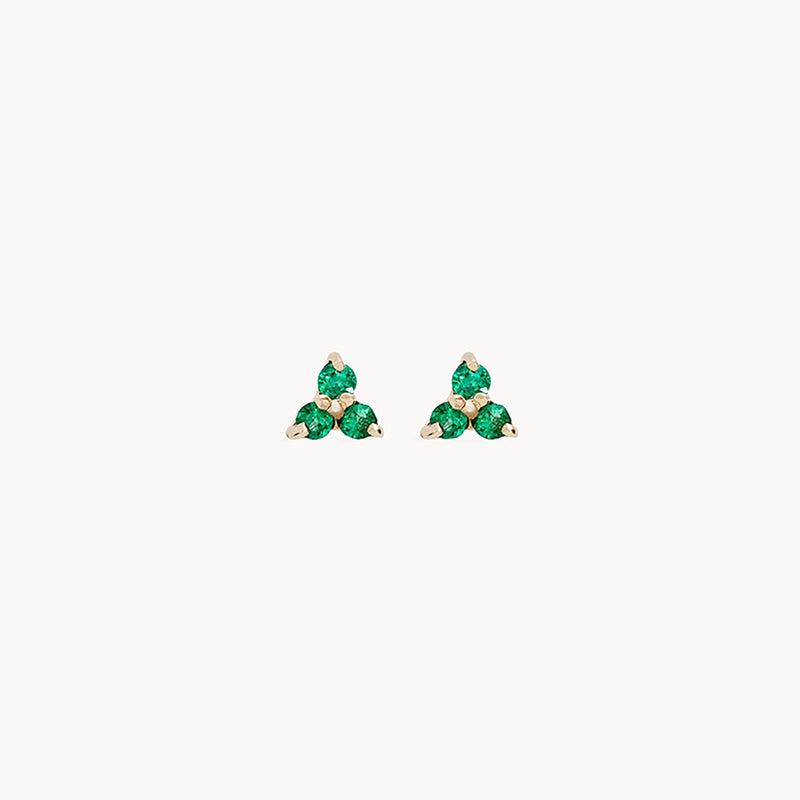 A pair of small, gold earrings named the "abacus tripod emerald earring - 14k yellow gold, emerald" by bluboho, featuring a triangular cluster of three green gemstones in each earring set in a minimalist design against a plain, white background.