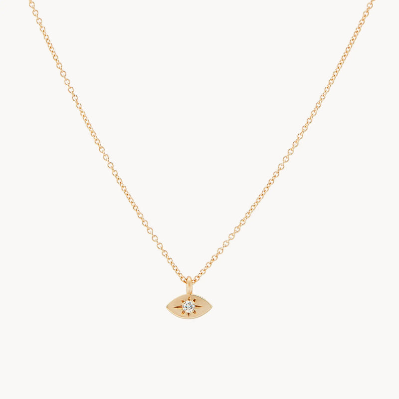 Introducing the visionary evil eye pendant by bluboho, a delicate 14k yellow gold necklace featuring a thin chain and a small, eye-shaped pendant adorned with a tiny, sparkling gem at its center. This minimalist and elegant design makes it an exquisite piece for any occasion.